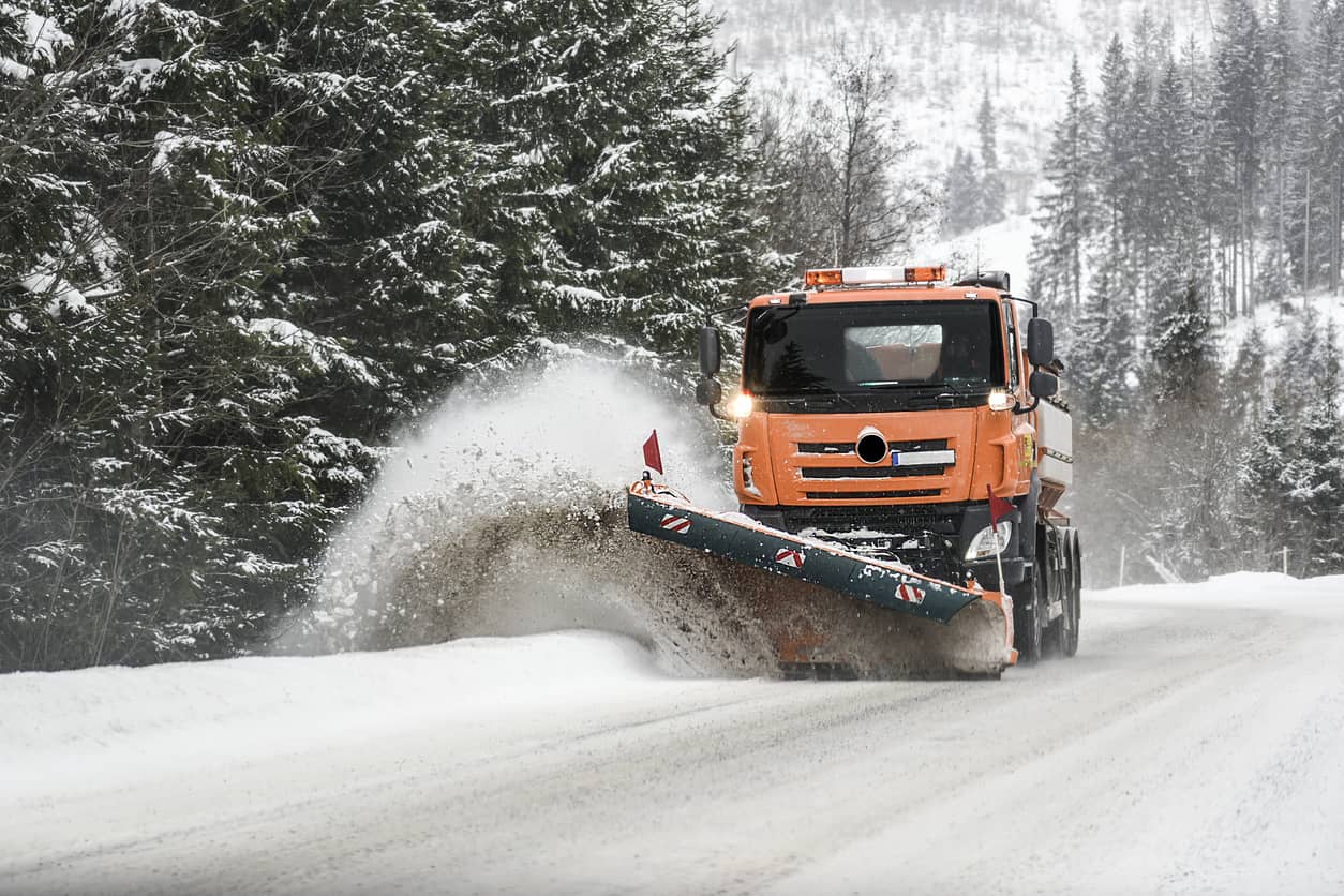 Lastebil brøyter snø i nordlig, snøbelagt terreng.